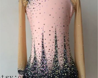 May include: A pink and black figure skating dress with long sleeves and a mesh overlay. The dress is decorated with rhinestones and has a black and white geometric pattern.
