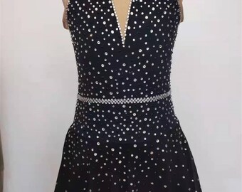 Op de afbeelding: Zwarte kunstschaatsjurk met halternek en een rok bedekt met strass.