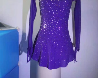 Puede incluir: Vestido de patinaje artístico morado con mangas largas y un diseño brillante. El vestido tiene una superposición transparente y está decorado con diamantes de imitación.