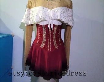 May include: A red and white figure skating dress with a white lace bodice and a sheer overlay. The dress is decorated with rhinestones and has long sleeves.