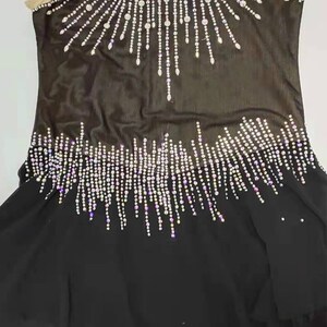 Könnte beinhalten: Ein schwarzer Tanz-Leotard mit einem Halterneck und einer transparenten Überlage. Der Leotard ist mit einem großen, funkelnden Strass-Design verziert.