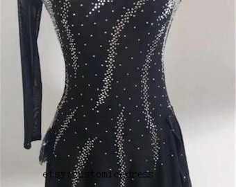Op de afbeelding: Zwarte kunstschaatsjurk met een lange mouw aan de ene kant en een korte mouw aan de andere kant. De jurk is versierd met strass in een geometrisch patroon.