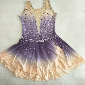May include: A purple and beige ombre figure skating dress with a beaded bodice and a layered skirt.