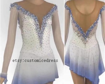 May include: A figure skating dress with a white bodice that fades to blue at the skirt. The dress features a sheer neckline and sleeves, embellished with blue and silver rhinestones. The text "etsy:customicedress" is visible.