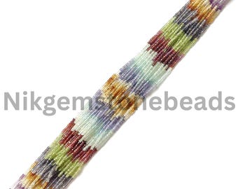 May include: Strand of colorful gemstone beads in shades of red, green, yellow, and purple. The beads are small and strung together, creating a textured, zig-zag pattern. The text "Nikgemstonebeads" is visible in the image.