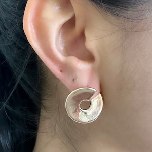 May include: Gold hoop earrings with a unique cut-out design. The earrings are a simple and elegant style.