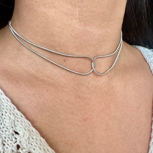 May include: A silver double-strand choker necklace with a unique interlocking design.