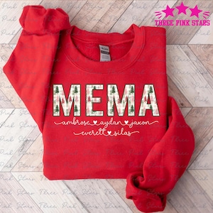 Può includere: Una felpa rossa con la scritta "MEMA" in un carattere a motivi con alberi di Natale. Sotto la parola ci sono i nomi Ambrose, Aydan, Jaxon, Everett e Silas in un carattere corsivo.