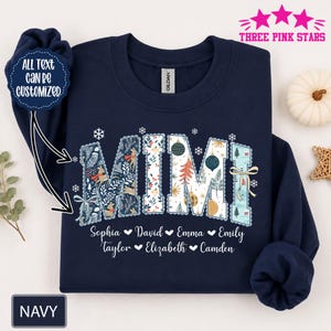 Könnte beinhalten: Ein marineblaues Sweatshirt mit dem Wort MIMI in großen, gemusterten Buchstaben, die mit Weihnachtsmotiven wie Rentieren, Ornamenten und Schneeflocken verziert sind. Unter dem Namen ist der Text Sophia, David, Emma, Emily, Taylor, Elizabeth und Camden gedruckt.