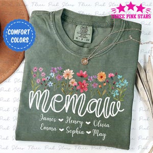 May include: A green t-shirt with a floral design and the word "memaw" in white script. Below the word are the names James, Henry, Olivia, Emma, Sophia, and May, separated by hearts.