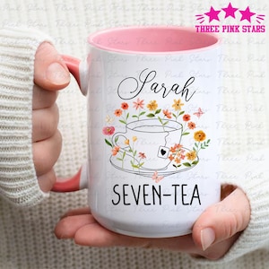 May include: White ceramic mug with a pink interior and handle, featuring the name "Sarah" in cursive above a teacup design with flowers and butterflies. The text "SEVEN-TEA" is below the teacup. The mug has the text "THREE PINK STARS" at the top.