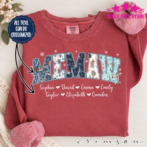 Può includere: Una felpa rossa a girocollo con la parola MEMAW in grandi lettere stampate con motivi natalizi. Sotto il testo, i nomi Sophia, David, Emma, Emily, Taylor, Elizabeth e Camden sono stampati in bianco. Un grafico blu indica ALL TEXT CAN BE CUSTOMIZED.