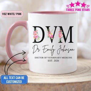 May include: White and pink ceramic mug with the letters "DVM" in black, adorned with floral accents. The mug features the name "Dr. Emily Johnson" and the text "DOCTOR OF VETERINARY MEDICINE EST. 2026". The mug has a pink handle and interior.