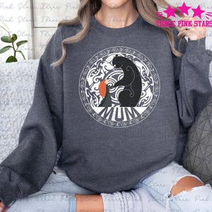 May include: A dark gray sweatshirt with a white circle design featuring a bear and a girl with the word "MUM" in the center.