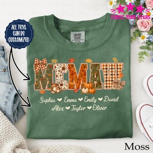 Könnte beinhalten: Ein moosgrünes T-Shirt mit dem Wort MEMAW in großen Buchstaben, verziert mit herbstlichen Mustern wie Kürbissen, Pilzen und Karomustern. Unter dem Text sind die Namen Sophia, Emma, Emily, David, Alex, Taylor und Oliver aufgedruckt.
