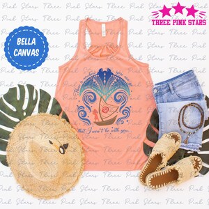 Op de afbeelding: Een perzikkleurig tanktop met een blauw en groen grafisch ontwerp met een boot en de tekst "There is nowhere you can go that I won't be with you..." Het tanktop ligt op een wit oppervlak met een strohoed, sandalen en een blauwe spijkerbroek.