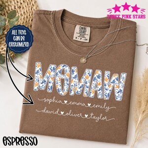Könnte beinhalten: Ein braunes kurzärmeliges T-Shirt mit dem Wort "MOMAW" in einem blau-orangen Blumenmuster. Unter dem Wort sind in zwei Zeilen in weißer Schreibschrift die Namen "sophia", "emma", "emily", "david", "oliver" und "taylor" durch Herzen getrennt.