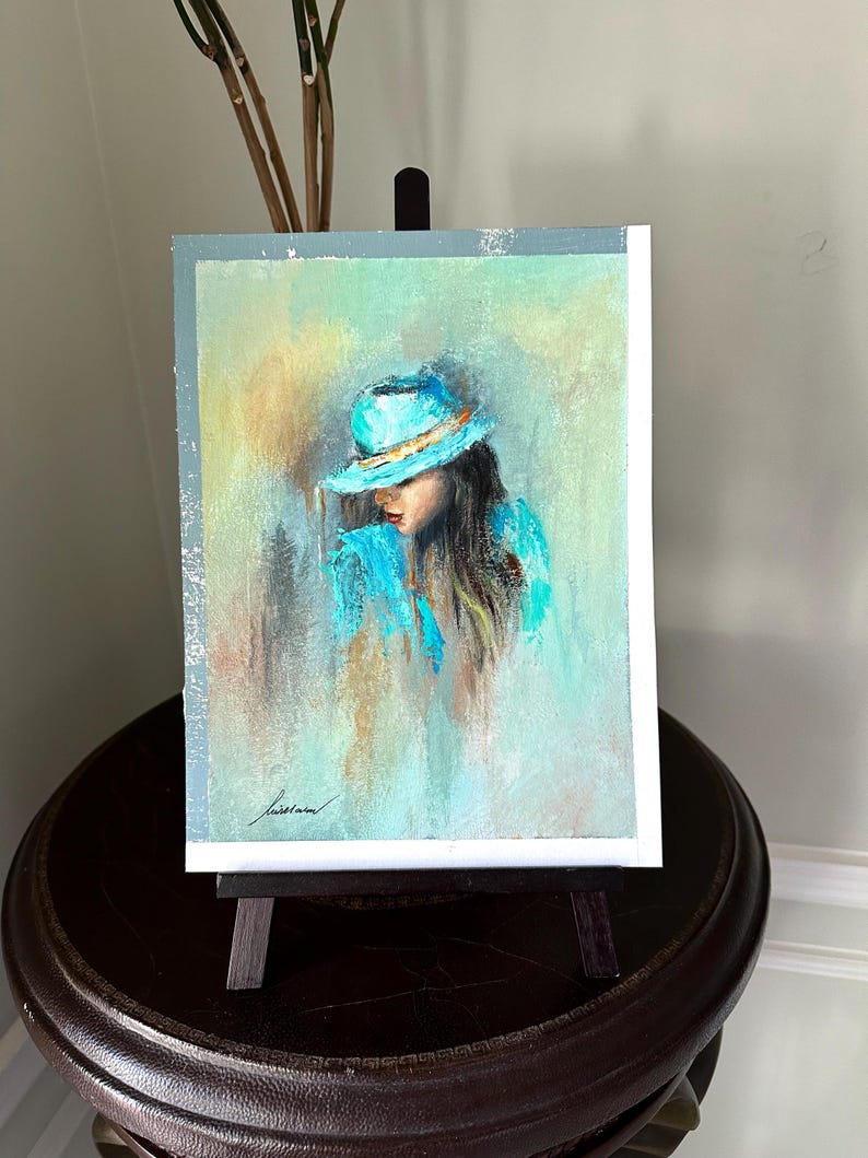 May include: A painting of a woman wearing a light blue hat and a light blue jacket. The background is a soft, abstract blend of light blue, green, and yellow.