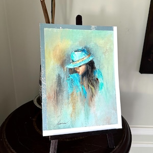 May include: A pastel painting of a woman wearing a turquoise hat and a turquoise jacket. The background is a soft blend of yellow, green, and blue.