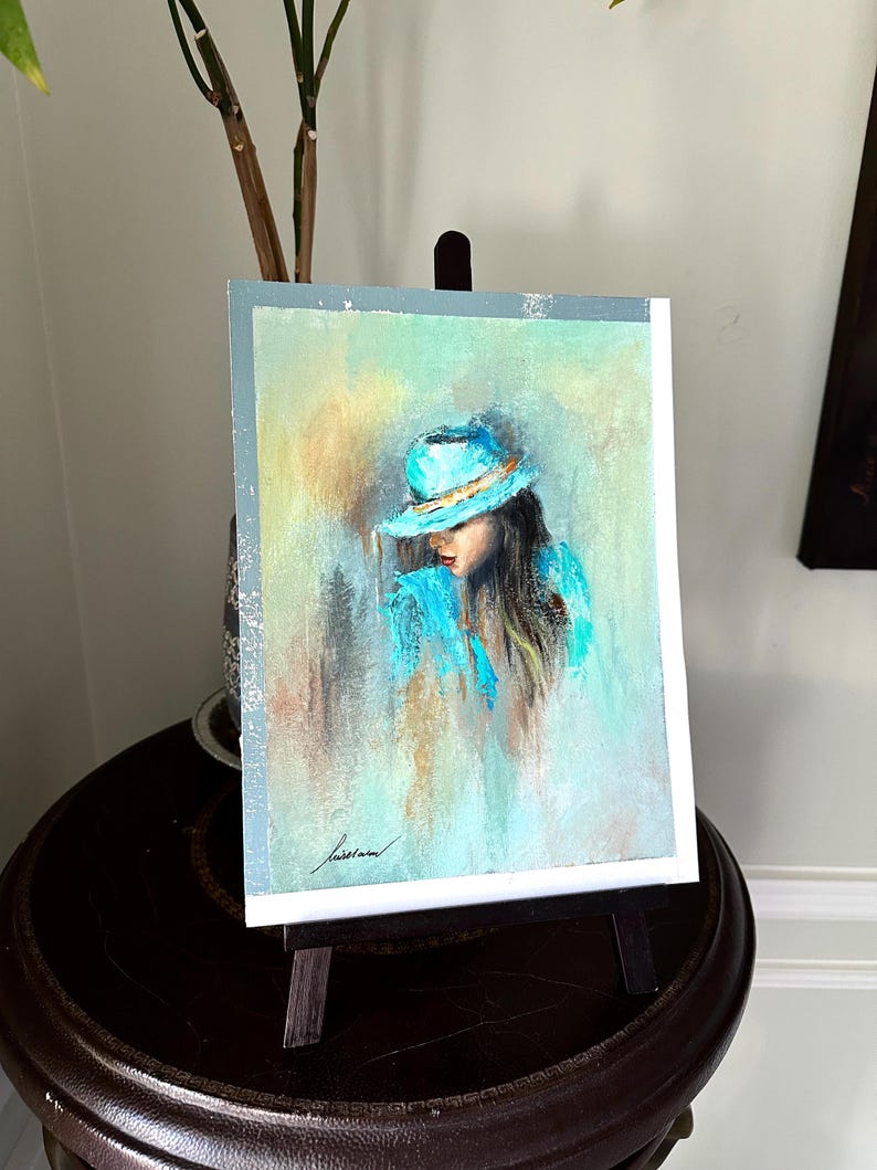 May include: A pastel painting of a woman wearing a turquoise hat and a turquoise jacket. The background is a soft blend of yellow, green, and blue.