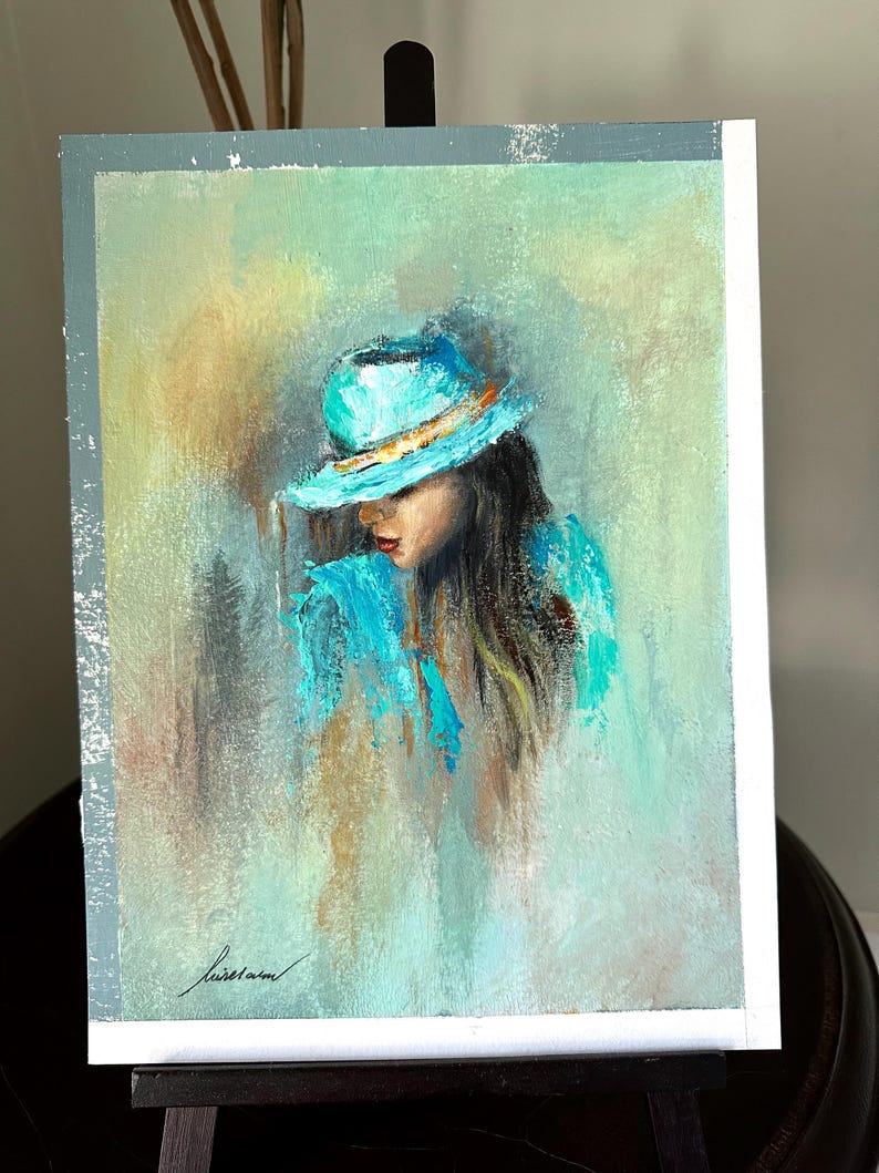 May include: A painting of a woman with long brown hair wearing a turquoise hat and a turquoise shirt. The background is a soft green and blue.