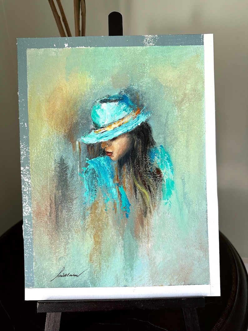 May include: A painting of a woman with long brown hair wearing a turquoise hat and a turquoise shirt. The background is a soft green and blue.