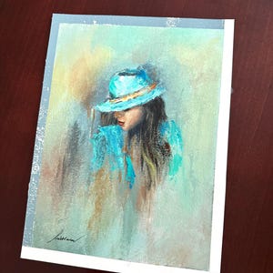 May include: A painting of a woman wearing a turquoise hat with a gold band. The woman's hair is long and dark, and she is looking down. The background is a soft, muted green and yellow.