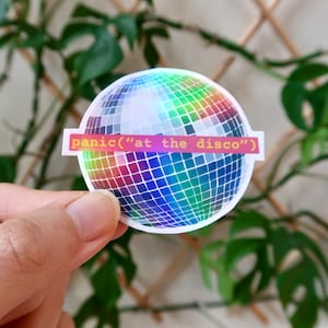 May include: A holographic sticker of a disco ball with the text "panic("at the disco")" printed on a pink and orange banner.