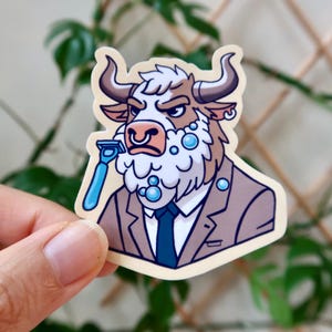 May include: A sticker featuring a cartoon bull with a serious expression, shaving with a blue razor. The bull wears a suit and tie, with shaving cream bubbles around its face. The sticker has a cream-colored background.