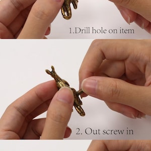 K&ouml;nnte beinhalten: Ein messingfarbener Metallknopf in K&auml;nguruform, dargestellt in einem dreistufigen Montageprozess. Der Text lautet: Hand-assembled knobs, 1. Drill hole on item, 2. Out screw in, 3. Screw with knob. Der Knopf zeigt eine detaillierte Tierfigur und eine Schraube.