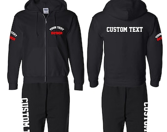 Pode incluir: Conjunto de fato de treino preto com casaco com capuz e calças de fato de treino. O casaco com capuz apresenta "YOUR TEXT DESIGN" em branco e vermelho e "CUSTOM TEXT". As calças de fato de treino têm "CUSTOM TEXT" impresso verticalmente.