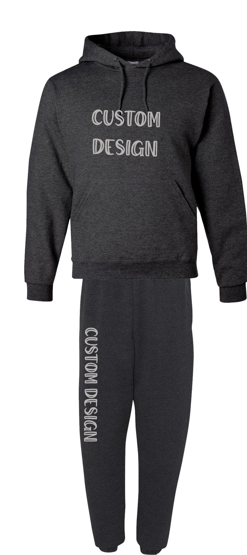 Pode incluir: Conjunto de moletom com capuz e cal&ccedil;as de moletom cinza carv&atilde;o. O moletom com capuz apresenta o texto "CUSTOM DESIGN" no peito, e as cal&ccedil;as de moletom t&ecirc;m o mesmo texto verticalmente na perna esquerda. Uma roupa confort&aacute;vel e casual.