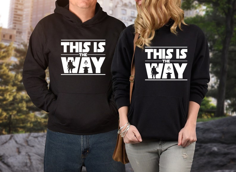 Puede incluir: Sudaderas con capucha negras con la frase "THIS IS THE WAY" en letras blancas. El dise&ntilde;o incluye una silueta de personaje y una peque&ntilde;a criatura. Las sudaderas tienen un bolsillo delantero.