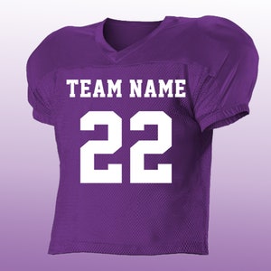 Peut inclure: Maillot de football am&eacute;ricain violet avec des lettres et des chiffres blancs. Le texte "TEAM NAME" est affich&eacute; au-dessus du num&eacute;ro "22". Le maillot a un col en V et des &eacute;paules rembourr&eacute;es.