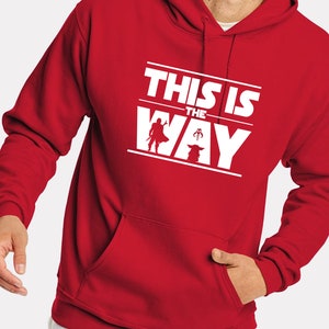 Puede incluir: Sudadera con capucha roja con un gr&aacute;fico blanco que dice "THIS IS THE WAY" con siluetas de personajes. La sudadera tiene un bolsillo delantero y una capucha con cord&oacute;n.