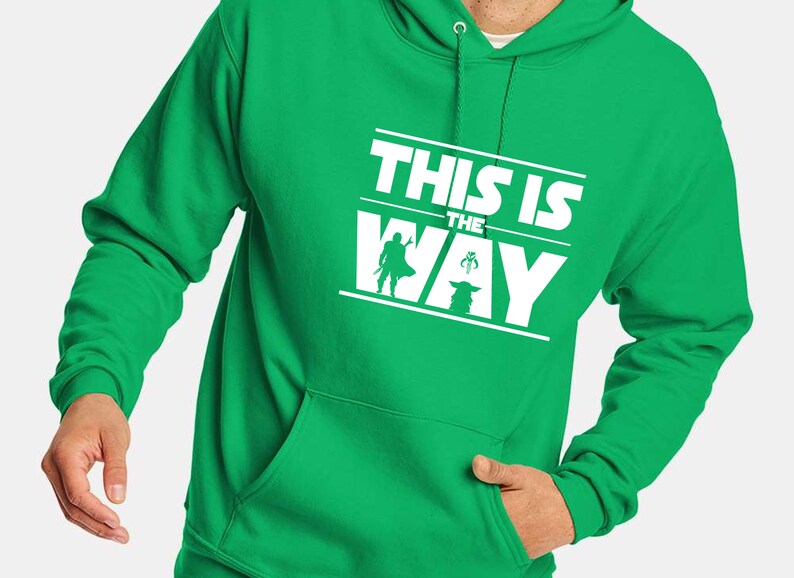 Puede incluir: Sudadera con capucha verde brillante con un gr&aacute;fico blanco que dice "THIS IS THE WAY". El dise&ntilde;o incluye siluetas de un personaje con capa, una criatura peque&ntilde;a y una figura con casco. Con bolsillo delantero.