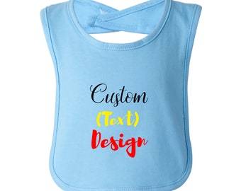 May include: A light blue baby bib with a rounded bottom and a neck strap that ties in the back. The bib has the words "Custom (Text) Design" printed on the front in black, yellow, and red.