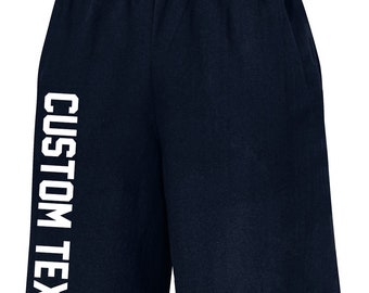 May include: Navy blue athletic shorts with a white elasticated waistband. The shorts have the words "CUSTOM TEXT" printed vertically in bold, white letters on the left leg. The shorts are made of a soft material.