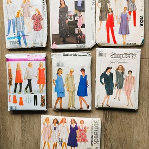 May include: A collection of seven sewing pattern envelopes from brands including McCall's, Simplicity, and Butterick. Each envelope features illustrations of various clothing styles such as dresses, tunics, and pants, with brand names and pattern numbers printed.