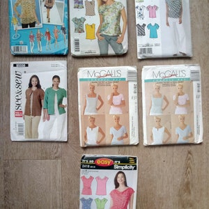 May include: A collection of seven sewing pattern envelopes from brands including Simplicity, McCall's, and See & Sew. Each envelope features illustrations or photographs of garments, including various tops, blouses, and jackets, with printed text and barcodes.