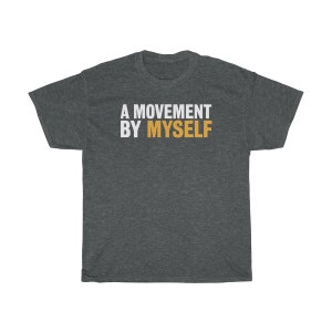 以下が含まれることがあります： 暗いヘザーグレーのTシャツに「A MOVEMENT BY MYSELF」という文字が白でプリントされており、「MOVEMENT」という単語はオレンジ色です。