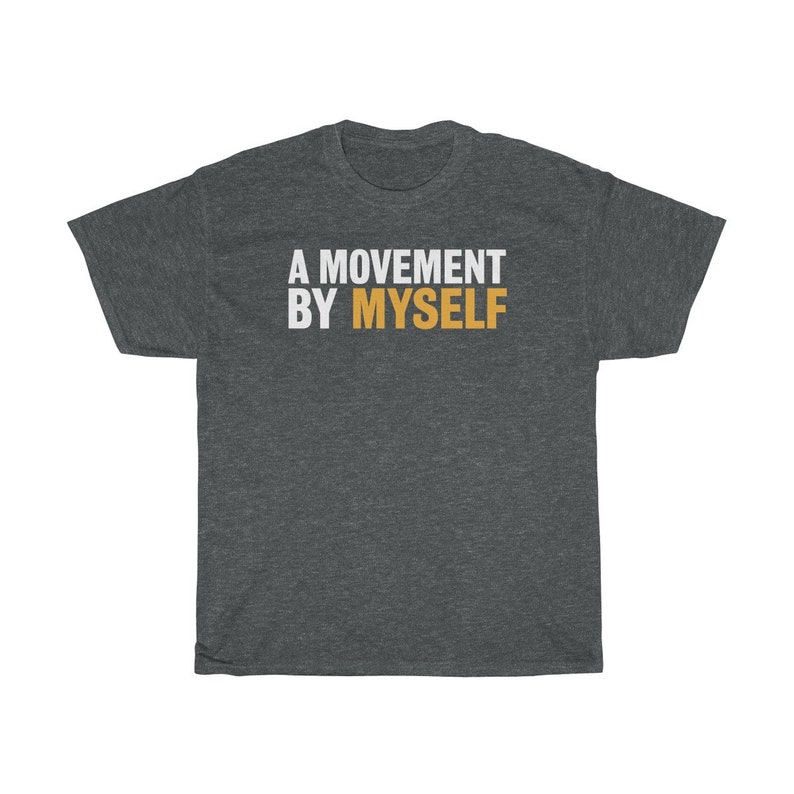 以下が含まれることがあります： 暗いヘザーグレーのTシャツに「A MOVEMENT BY MYSELF」という文字が白でプリントされており、「MOVEMENT」という単語はオレンジ色です。