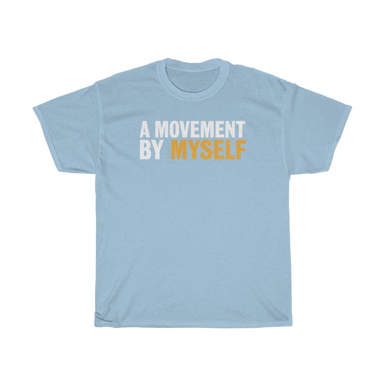 以下が含まれることがあります： 白とオレンジで「A MOVEMENT BY MYSELF」とプリントされた薄い青色のTシャツです。