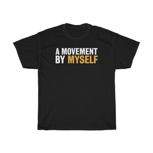以下が含まれることがあります： 黒いTシャツに白い文字で「A MOVEMENT BY MYSELF」と書いてあります。「BY」という単語はオレンジ色です。