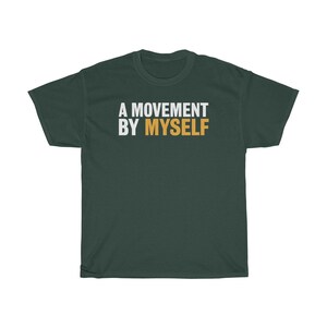 以下が含まれることがあります： 白とオレンジの文字で「A MOVEMENT BY MYSELF」と書かれた濃い緑色のTシャツです。