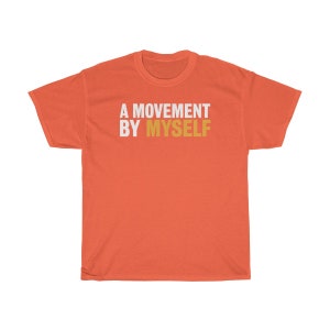 以下が含まれることがあります： コーラルオレンジのTシャツに、白い文字と金色の文字で「A MOVEMENT BY MYSELF」と書かれています。