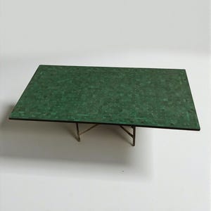 May include: A rectangular coffee table with a mosaic-style green top and a dark brown border. The table is supported by a delicate, light-colored metal frame. The table's dimensions are approximately 48 inches long and 24 inches wide.