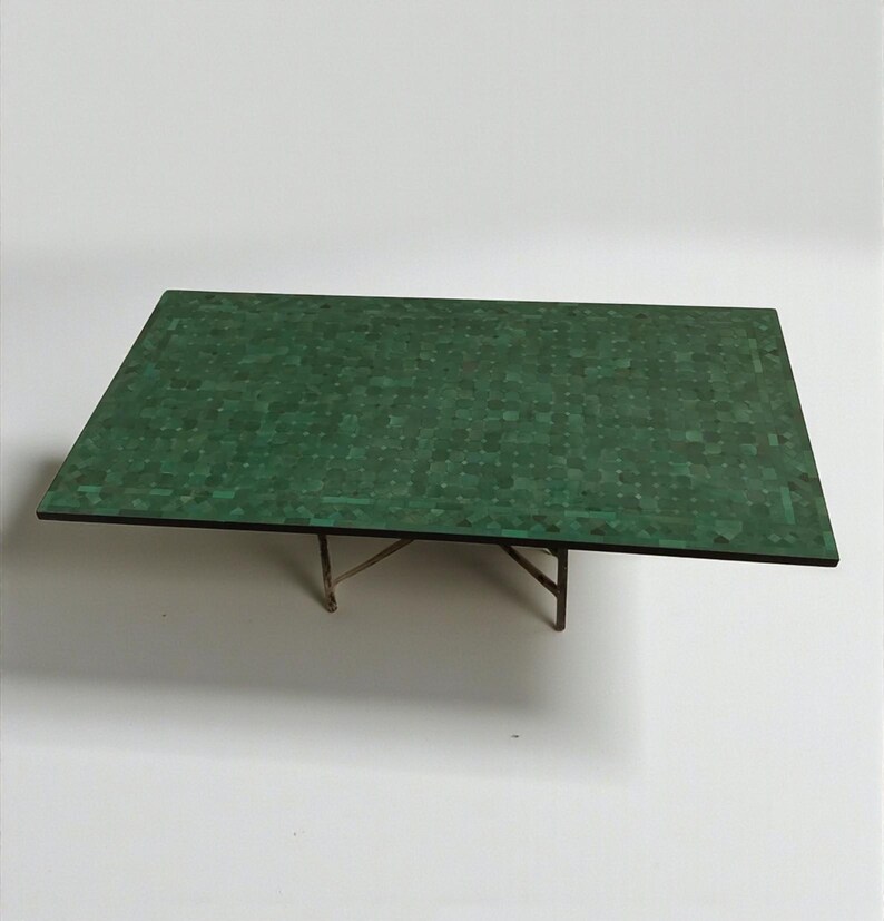 May include: A rectangular coffee table with a mosaic-style green top and a dark brown border. The table is supported by a delicate, light-colored metal frame. The table's dimensions are approximately 48 inches long and 24 inches wide.