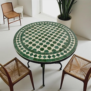 May include: A round table featuring a green and white geometric tile mosaic top with a star and diamond pattern, supported by a black metal frame with curved legs, accompanied by three wooden chairs with woven seats and backrests.