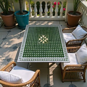 Peut inclure: Une table de terrasse rectangulaire avec un plateau en mosaïque verte et blanche orné d'un motif floral central, entourée de trois fauteuils en osier marron avec des coussins blancs. La table présente une bordure géométrique.